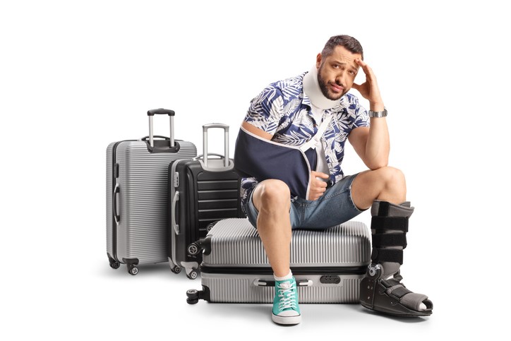 A person with a neck brace and a broken arm sitting on luggage

AI-generated content may be incorrect.